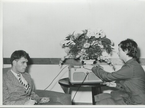 Alex seated in lounge room listening to tapes played by Carole Laird