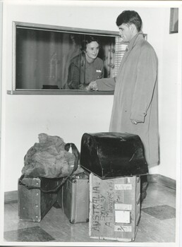 Alex standing with his luggage at reception with Mrs A Mann grasping his hand