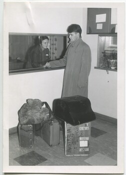 Alex standing with his luggage at reception with Mrs A Mann grasping his hand