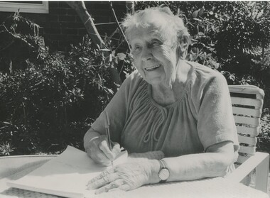Phyllis Pickford using a pen and notepad as she sits outside