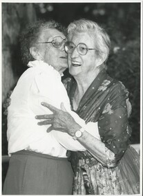 Two older woman hug and chat to each other