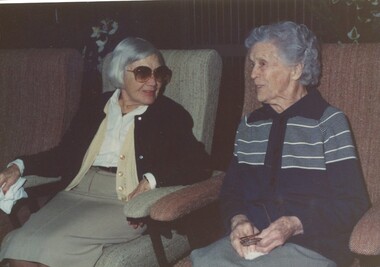 Two ladies seated in lounge chairs chatting to each other