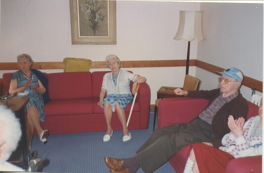 Four residents sit on red lounges, two clapping their hands
