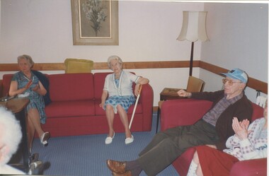 Four residents sit on red lounges, two clapping their hands