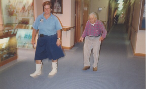 A nurse walks along the hallways with a resident following