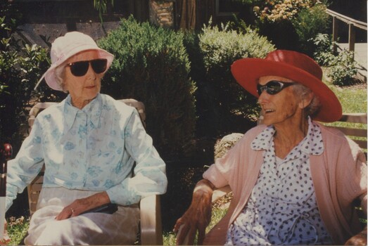 Two women sit outside and chat in the garden