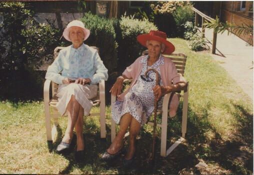 Two women sit outside and chat in the garden