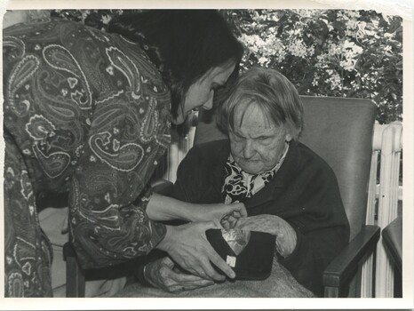 Female staff member helping a resident place something into bucket