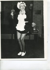Older woman smiles as she raises the skirt of her maid costume