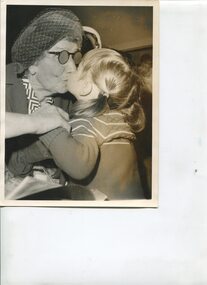 Woman wearing hat and gloves kissing a young child