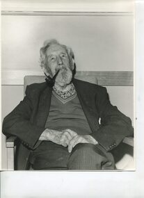 Older man smokes a pipe as he faces camera
