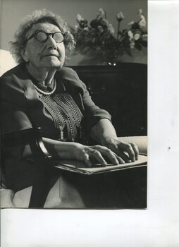 Older woman sits in lounge room reading Braille