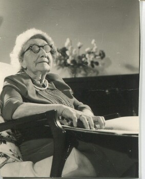 Older woman sits in lounge room reading Braille