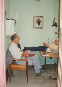 A suited man chats to a resident in his bedroom