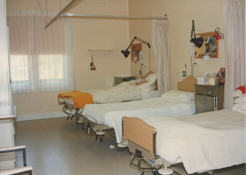 Two empty beds and one occupied in a shared bedroom