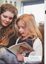Zoe and Sasha Skjellerup looking at a book