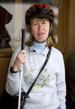 Woman wearing a bike helmet and holding a white cane