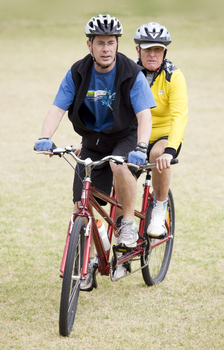 Man in yellow biking helmet riding with another man in blue