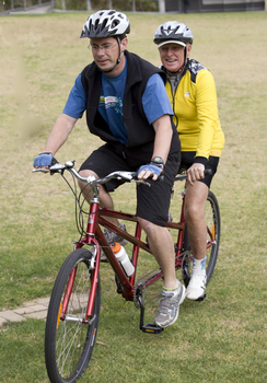 Man in yellow biking helmet riding with another man in blue