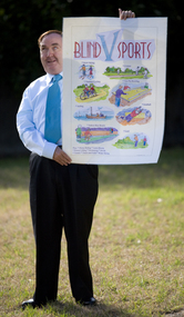 Maurice Gleeson holding a Blind Sports Victoria poster