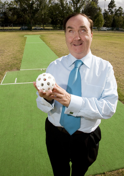 Maurice Gleeson holding an audible ball used in blind cricket whilst standing next to a cricket pitch