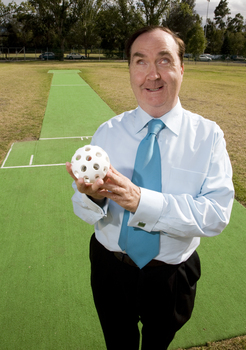 Maurice Gleeson holding an audible ball used in blind cricket whilst standing next to a cricket pitch