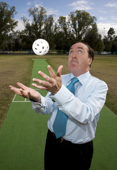 Maurice Gleeson tossing an audible ball used in blind cricket whilst standing next to a cricket pitch