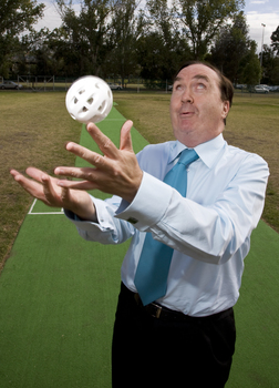 Maurice Gleeson tossing an audible ball used in blind cricket whilst standing next to a cricket pitch
