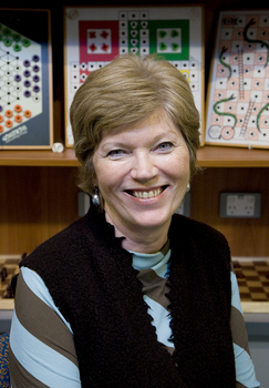 Woman smiles as she looks to camera with board games in the background