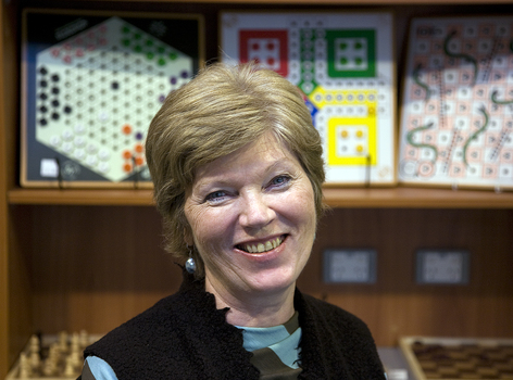 Woman smiles as she looks to camera with board games in the background