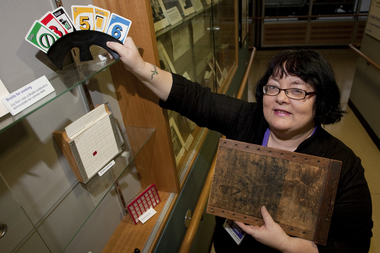 Michele Prentice holding a card holder with Braille UNO cards and a base board for a braille frame