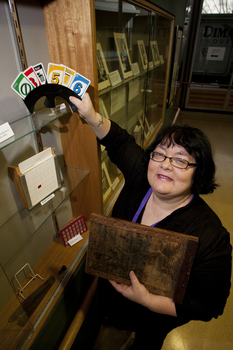 Michele Prentice holding a card holder with Braille UNO cards and a base board for a braille frame