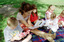 Sigrid and various children sit on a picnic blanket in a grassed area