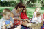 Sigrid and various children sit on a picnic blanket in a grassed area