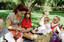 Sigrid and various children sit on a picnic blanket in a grassed area