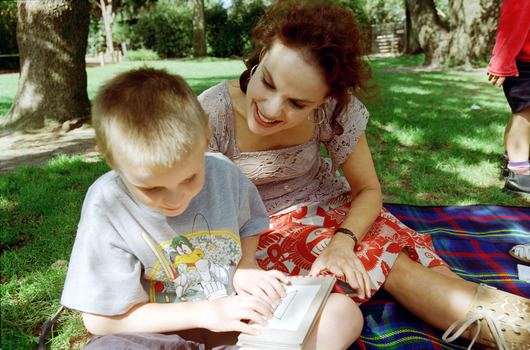 Sigrid and various children sit on a picnic blanket in a grassed area