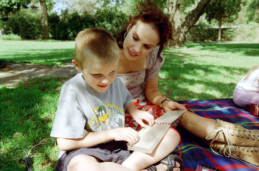 Sigrid and various children sit on a picnic blanket in a grassed area
