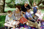 Sigrid and various children sit on a picnic blanket in a grassed area