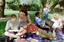 Sigrid and various children sit on a picnic blanket in a grassed area