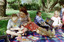 Sigrid and various children sit on a picnic blanket in a grassed area