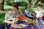 Sigrid and various children sit on a picnic blanket in a grassed area