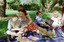 Sigrid and various children sit on a picnic blanket in a grassed area