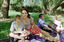 Sigrid and various children sit on a picnic blanket in a grassed area