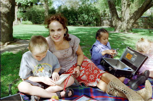 Sigrid and various children sit on a picnic blanket in a grassed area