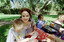 Sigrid and various children sit on a picnic blanket in a grassed area