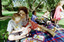 Sigrid and various children sit on a picnic blanket in a grassed area