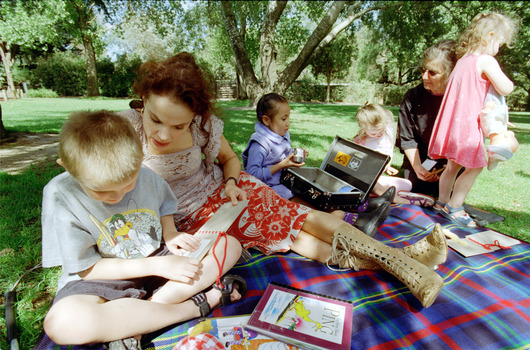 Sigrid and various children sit on a picnic blanket in a grassed area