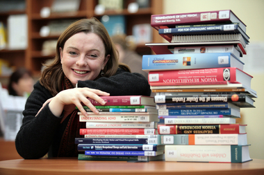 Renee leaning on a pile of books in the browsing library