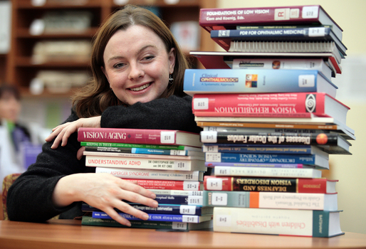 Renee leaning on a pile of books in the browsing library