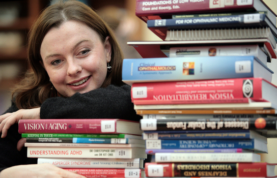 Renee leaning on a pile of books in the browsing library